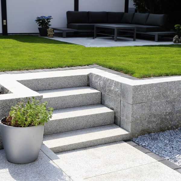 Gepflegter Ziergarten mit Granitmauer und Blockstufentreppe